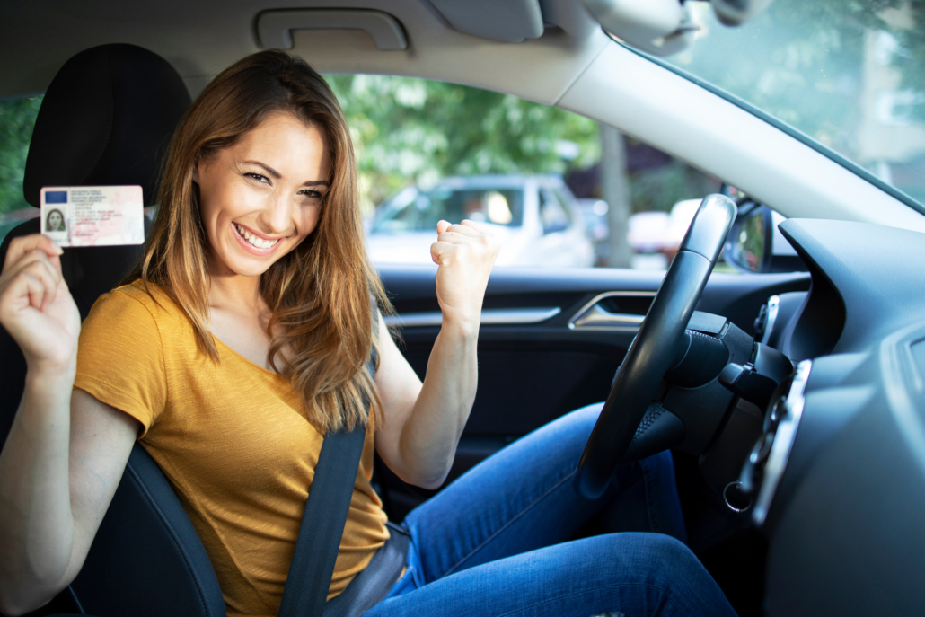 junge frau im auto mit führerschein in der hand glücklich bestandene Prüfung